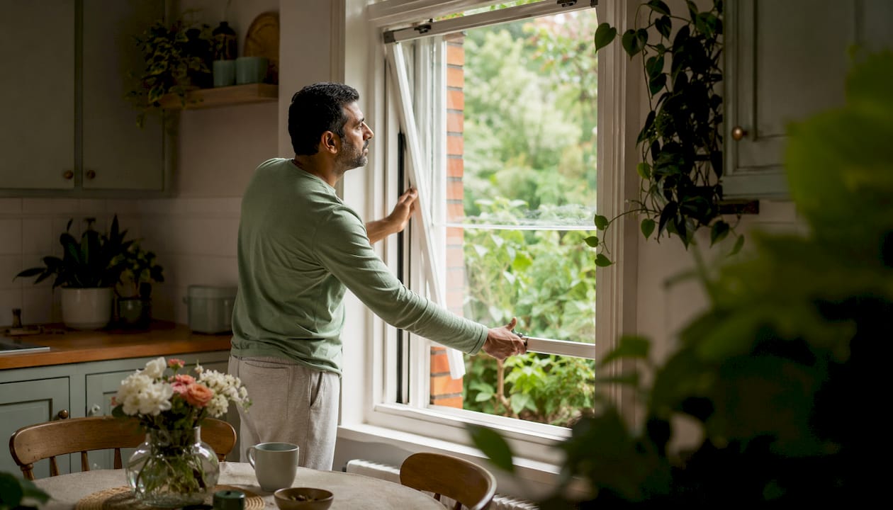 Man opening bedroom window for ventilation